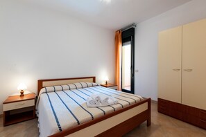 Un lit bien fait, avec une couvre-lit à rayures, une lampe de chevet, une table de chevet et une armoire.