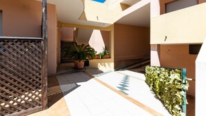 A courtyard with a metal gate, potted plants, and a tiled floor. - Apartment in the city with balcony and a view – Apartment Cavour H (Villasimius)