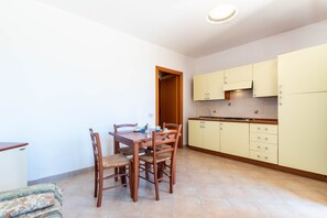 Une cuisine compacte comprenant une table et des chaises, un petit évier et des meubles de couleur claire.