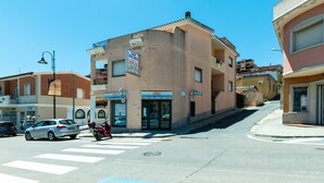 A street view with a building featuring a signboard, a pedestrian crossing, and a car. - Apartment in the city with balcony and a view – Apartment Cavour H (Villasimius)