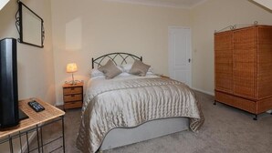 A bedroom with a bed, a bedside table with a lamp, a television, and a wardrobe.
