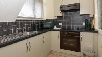 Compact kitchen with microwave, stainless steel sink, and dishwasher.
