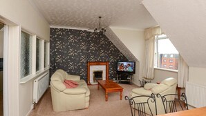 A living room with a fireplace, a television, and a dining area.