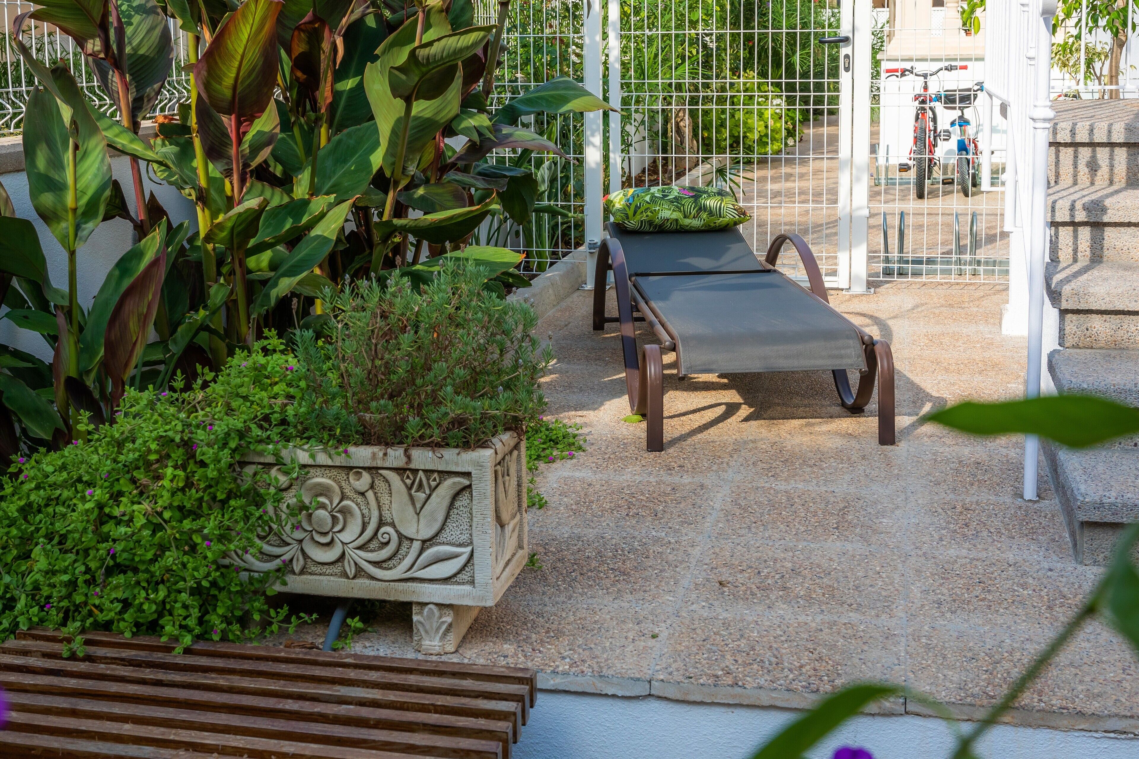 Un espace jardin agrémenté d’un banc, d’un bac à fleurs décoratif et d’une clôture en métal.