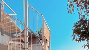 Eine Wendeltreppe führt zu einem Balkon mit Blick auf den Strand.
