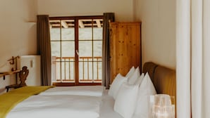 A hotel room with a bed, a wooden wardrobe, a window with a view, and a bedside table with a lamp. - Luxurious Chalet with Jacuzzi, Dreamlike Interior, Wi-Fi and Garden (La Valle Agordina)