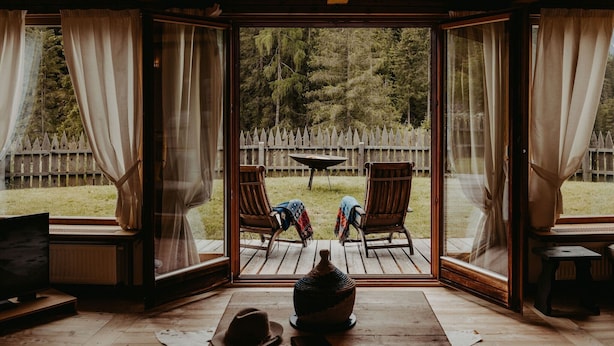 A room with a large sliding glass door leading to an outdoor deck with two chairs and a table. - Luxurious Chalet with Jacuzzi, Dreamlike Interior, Wi-Fi and Garden (La Valle Agordina)