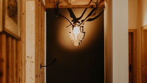 A wooden interior with a deer head mounted on the ceiling, a blue chair, and a wooden floor. - Luxurious Chalet with Jacuzzi, Dreamlike Interior, Wi-Fi and Garden (La Valle Agordina)