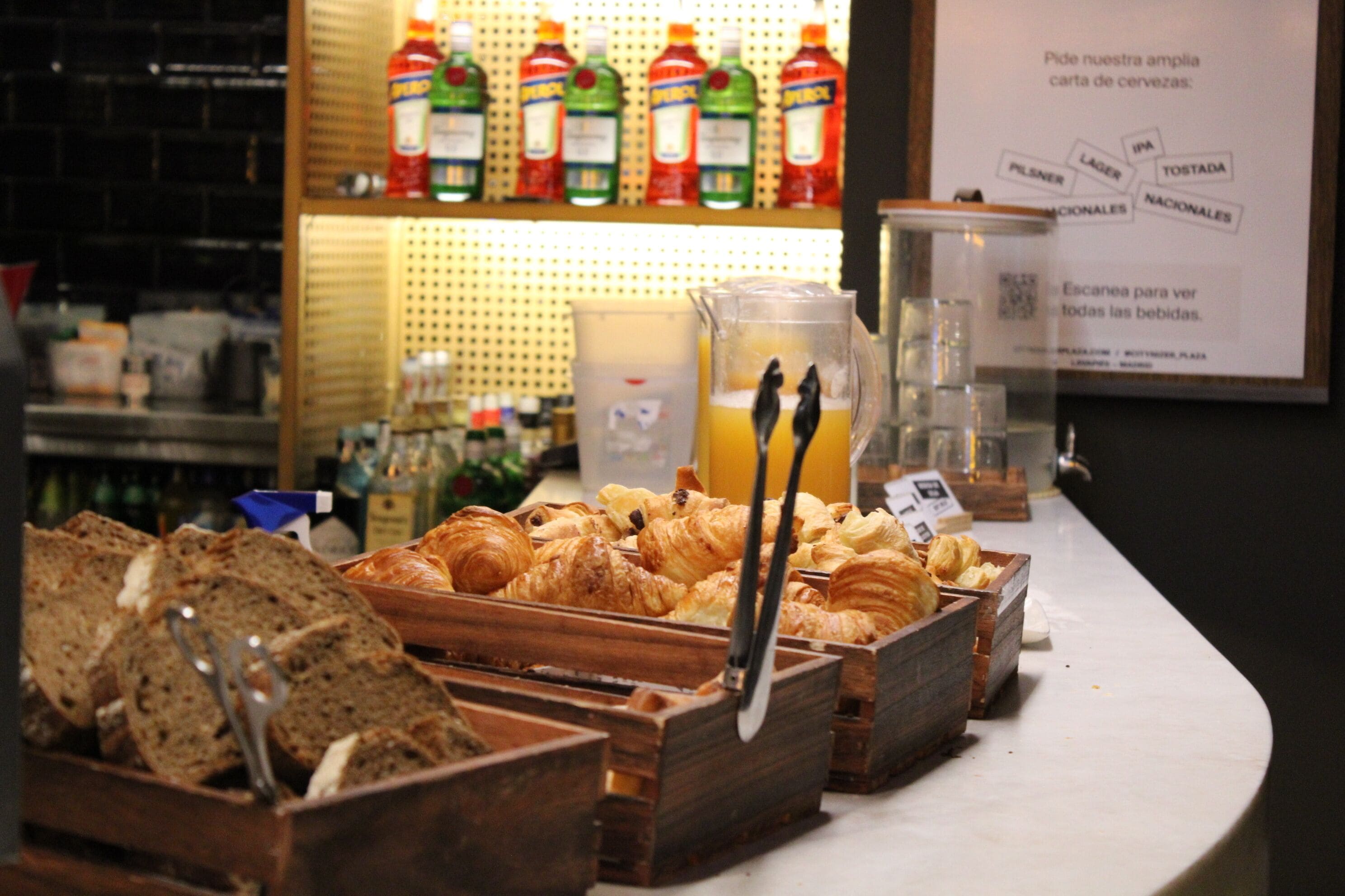 A breakfast buffet with bread, pastries, and a selection of beverages.