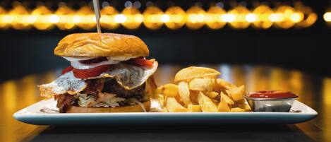 A plate with a burger, fries, and a small container of ketchup.