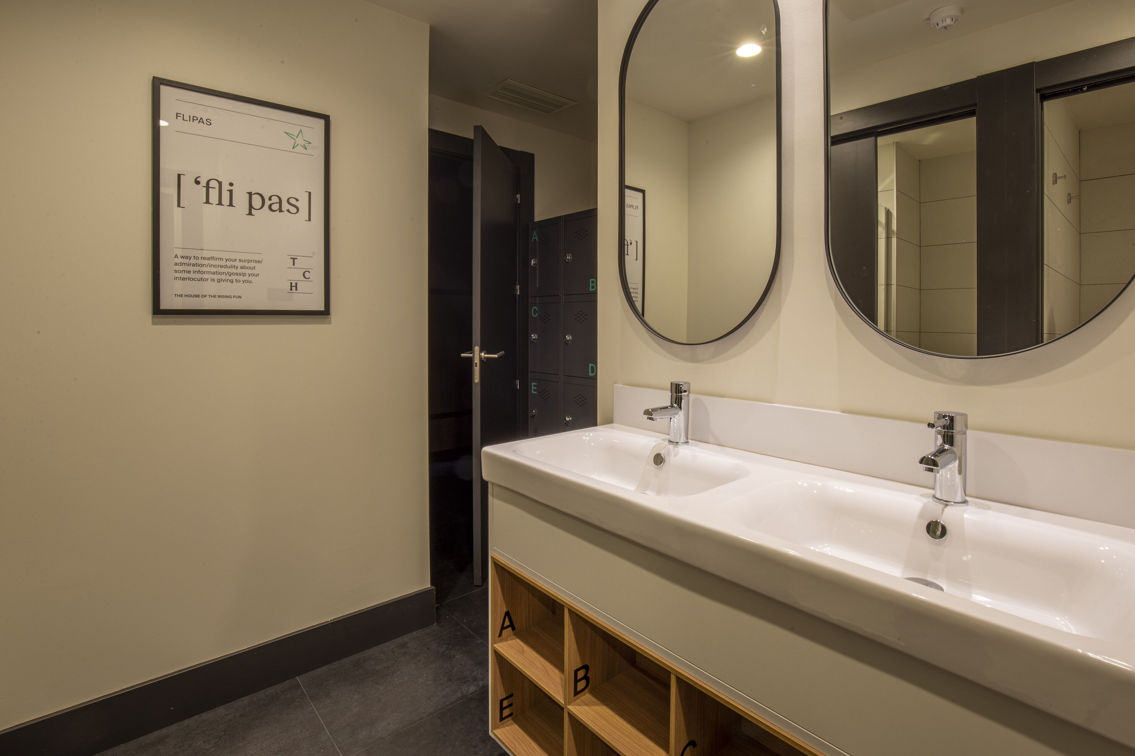 Un baño moderno con un lavabo blanco grande, dos espejos y un cartel en la pared.