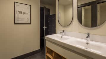 Un baño moderno con un lavabo blanco grande, dos espejos y un cartel en la pared.