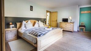 A bedroom with a wooden bed, bedside tables, a dresser, a mirror, and a television.