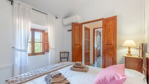A bedroom with a bed, a bedside lamp, a window with curtains, and a view of the outside. - Villa on the Beach with Sea View in Port de Soller. Garden and Wi-Fi (Sóller)