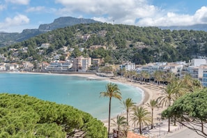 Une ville côtière avec des bâtiments, une plage et une chaîne de montagnes en arrière-plan.