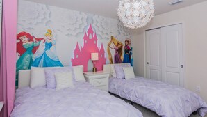 Une chambre avec deux lits, une décoration murale représentant un château rose et un lustre.