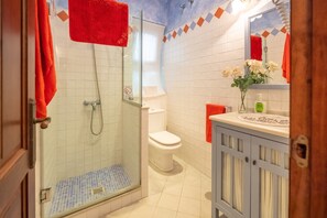 A bathroom with a glass-enclosed shower, a toilet, and a vanity with a mirror.