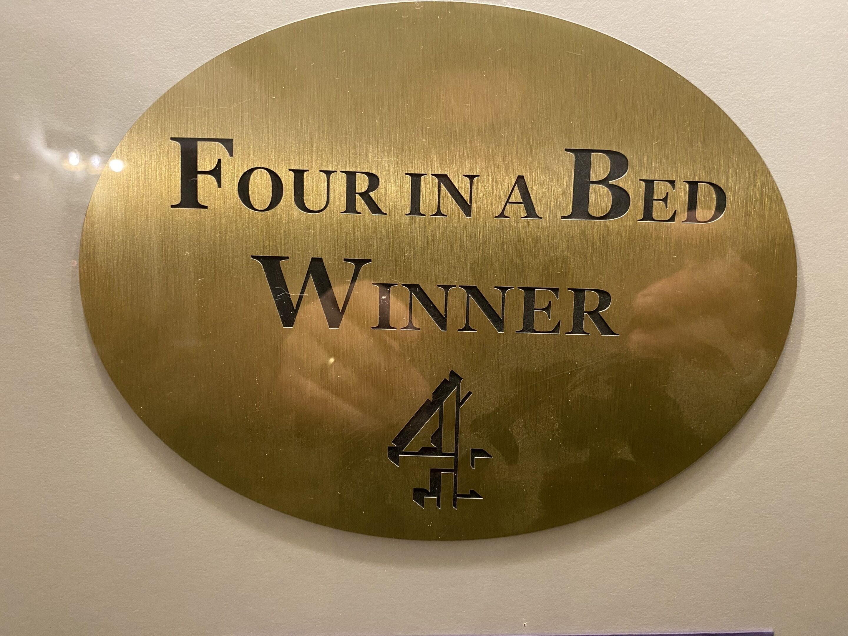 Eine runde Plakette mit dem Text: ‚Four in a Bed Gewinner 4‘.