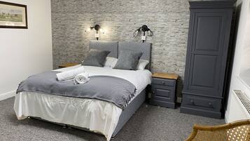 Un dormitorio con cama, ropa de cama gris, un armario gris y un aplique en la pared.