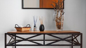 A wooden table with a woven basket, a black vase, and a clear vase with dried plants. - Charming Holiday Apartment with Terrace (Barbate)