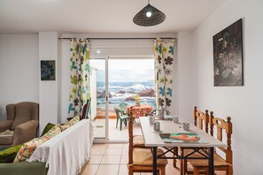 Uma sala de jantar com mesa, cadeiras e vista para o oceano.