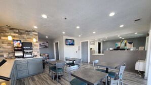 Una cocina moderna con cafetera, televisor y un cartel de bienvenida.