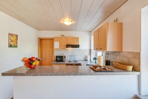 A kitchen with a granite countertop, a microwave, a stove, and a sink.