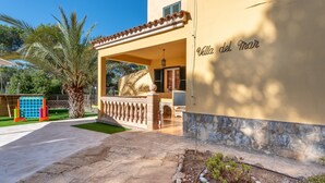 A building with a balcony, a palm tree, and a sign reading 'Villa del Mar'.