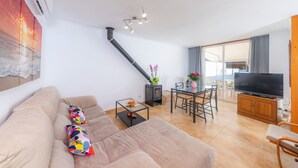 A modern living room with a sofa, a glass coffee table, a TV, and a fireplace. - Near the Beach and with Terrace - Can Bennasar (Can Picafort)
