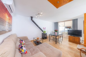 Un salon moderne avec un canapé, une table basse en verre, un téléviseur et une cheminée.