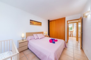 Une chambre à coucher avec un lit, une table de chevet, une lampe et une vue sur l’extérieur.