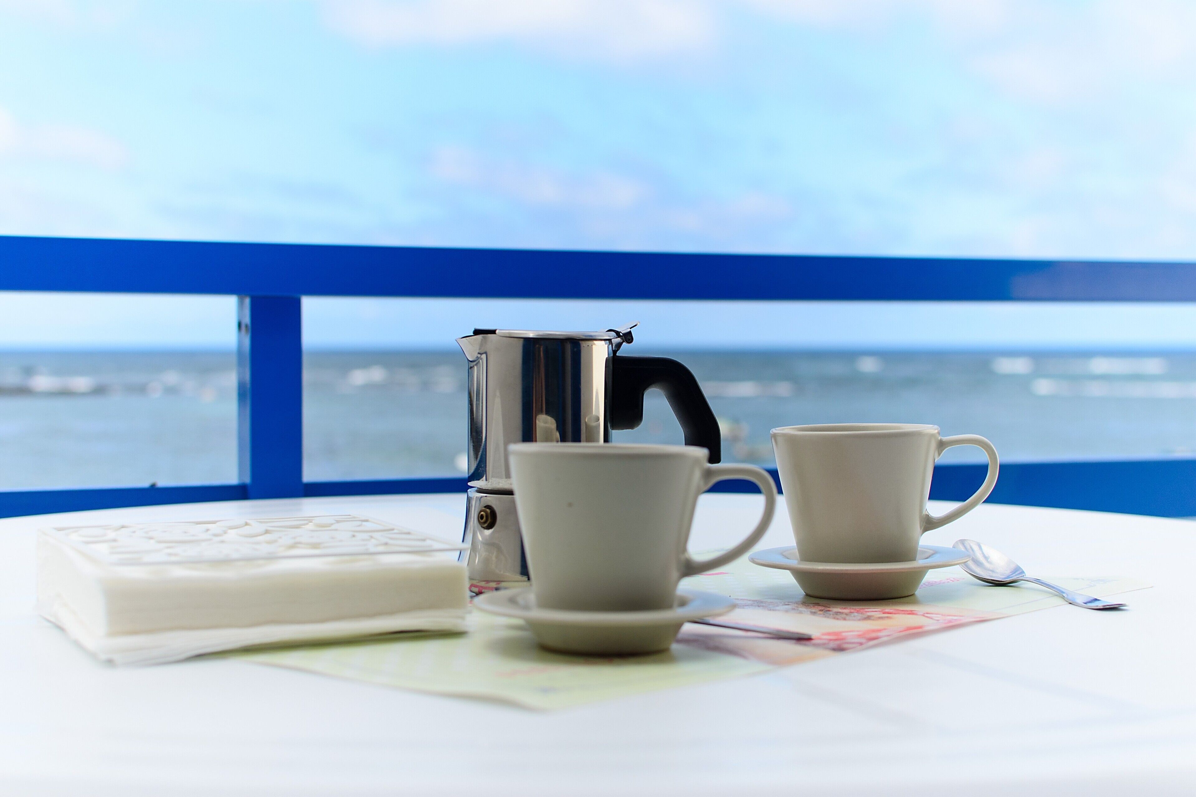 Une table avec une machine à café, deux tasses, une cuillère et un savon.