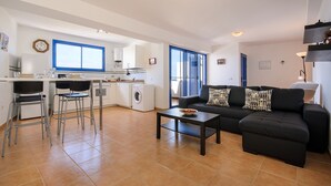 Un appartement moderne comprenant une cuisine, un coin repas et un salon, et aménagé avec un canapé, une table basse et un lave-linge.