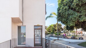 Un edificio de fachada blanca, puerta de vidrio y baranda metálica.