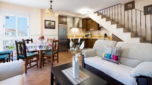 Una cocina moderna con horno empotrado, un área de comedor con mesa y sillas, y una escalera que lleva a un nivel superior.
