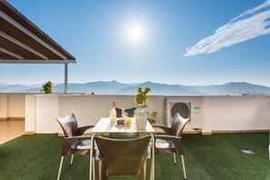 A dining area with a table set for two, a bottle of wine, and a pitcher of water. - "Guadalhorce Penthouse" Solarium with Valley Views, 2 Private Terraces and Wi-Fi (Álora)