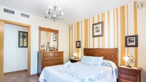 Un dormitorio con una cama grande, cómoda de madera y una mesita de noche con lámpara.
