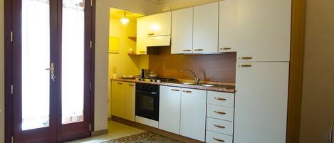 Een koelkast, een oven, een kookplaat, kookgerei, borden en bestek