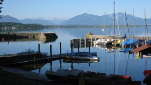 A marina with boats docked, a dock, and mountains in the background. - Holiday Apartment “Beim Paulfischer - Eckbankerl” Close to Chiemsee with Balcony & Terrace (Chieming)
