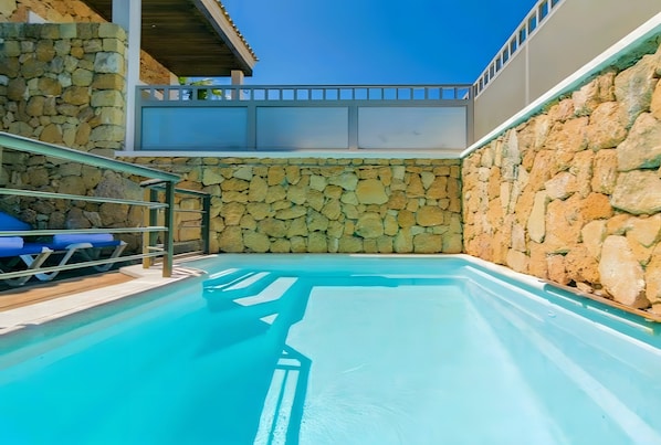 A swimming pool with stone walls and a metal railing.