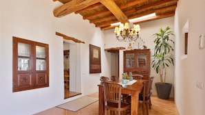 Un comedor con mobiliario de madera, una araña y una planta en maceta.