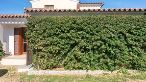 Une maison avec un toit en tuiles, une porte en bois et un arbuste taillé avec soin.