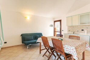 Ein Essbereich mit Tisch, Stühlen, einer Couch und einer Küche im Hintergrund.