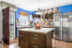 A kitchen with a central island, stainless steel appliances, and colorful tiles on the wall.
