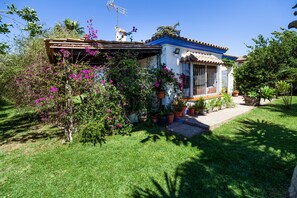 A house with a tiled roof, a small porch, and potted plants.