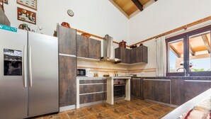 A kitchen with a refrigerator, oven, microwave, and wooden cabinets. - Embedded in Nature and with Pool - Finca Esplendor (CAMPOS)