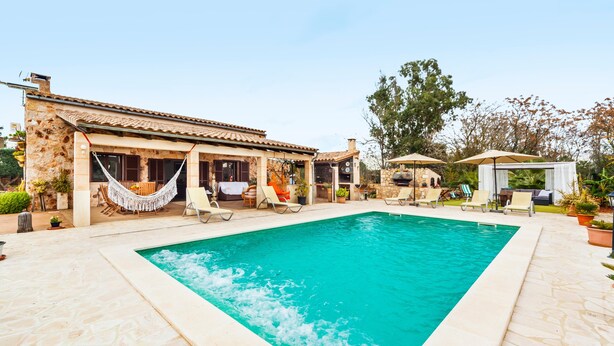 A pool area with a stone building, lounge chairs, and umbrellas. - Embedded in Nature and with Pool - Finca Esplendor (CAMPOS)
