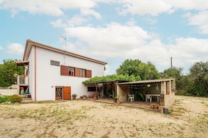 A two-story house with a patio area, a small covered seating area, and a garden.