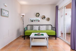 A room with a green sofa, a white coffee table, a floor lamp, and hexagonal wall decorations.
