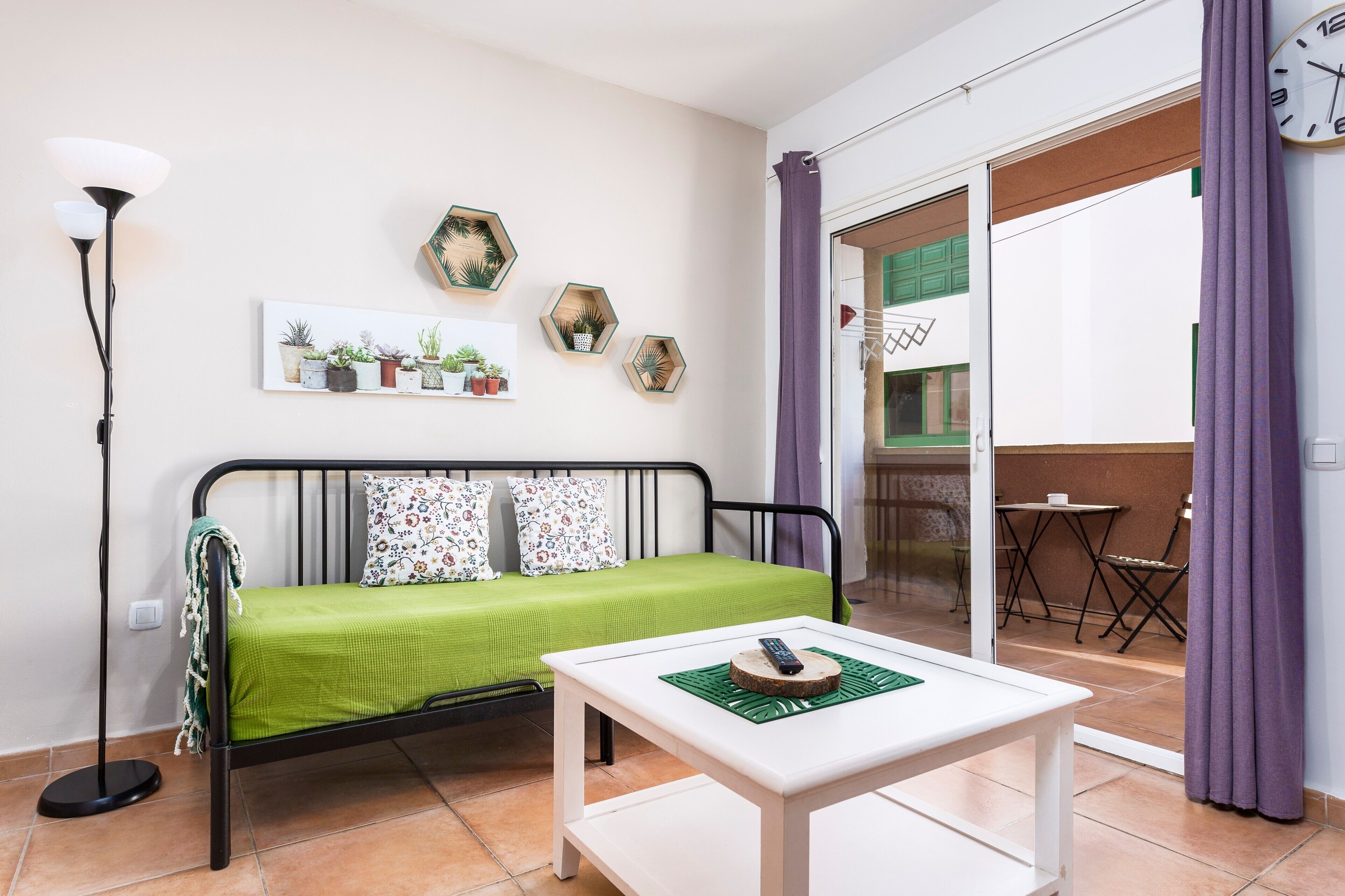 Une chambre avec un lit, une table, une lampe sur pied et un balcon équipé d’une table et de chaises.
